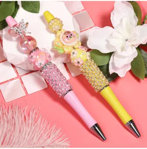 DIY handmade beaded ballpoint pen detail view showcasing sparkling rhinestones and cute floral charms.