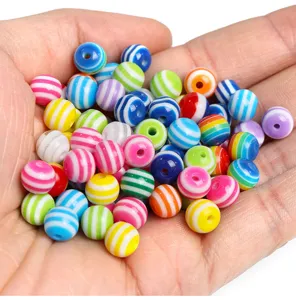 Close-up detail showing colorful striped resin beads held in hand, ideal for DIY jewelry making.