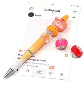 Handmade DIY beaded pen set with rhinestone pumpkin beads and camera charm detail.