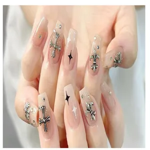 Close-up van press-on nagels met zilveren metalen kruis bedels en fonkelende strass steentjes.