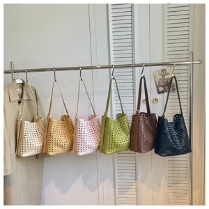 Vue détaillée de sacs à main seau tissés et ajourés suspendus sur un portant en divers coloris.