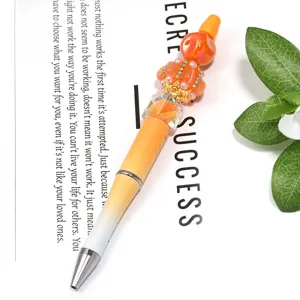 Stylo à bille DIY avec corps dégradé orange et ornements en strass sur fond blanc propre