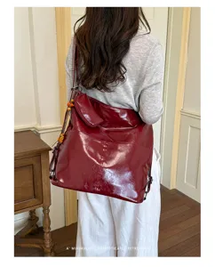 Detail view of the burgundy PU leather convertible backpack showing front pocket and strap design