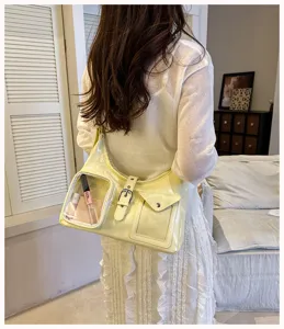 Detail shot of trendy yellow shoulder bag with transparent pocket and metal buckle decor.
