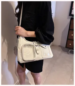 Detail shot of white patent leather ita bag with clear window pockets and metal buckle.