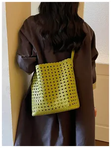 Détail de sac porté épaule en cuir tissé vert avec motif en losanges et texture souple.