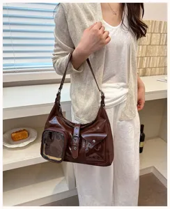 Detail shot of dark brown patent leather shoulder bag with transparent pocket and retro buckle.