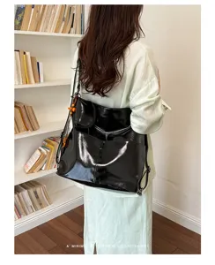Detail of black glossy PU leather convertible backpack showing texture, multi-pockets and straps.