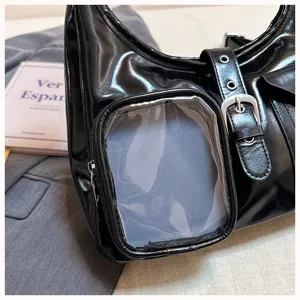 Close-up detail of the black glossy ita shoulder bag with transparent pocket window and metal buckles.