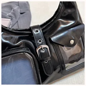 Close-up detail view of black glossy ita bag, clear window pockets and metal buckle.