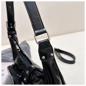 Black PU leather shoulder bag detail, metallic buckle and rivet hardware, fashion design.