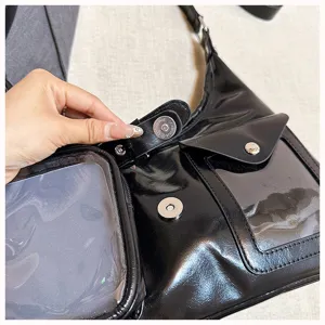 Black glossy shoulder bag detail showing clear window pocket and metal magnetic snap closure.