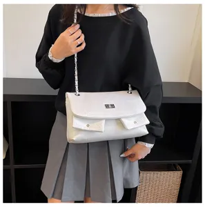 Modell-Detailansicht einer stilvollen weißen Schultertasche mit Kette und Taschen.