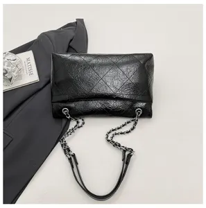 Detailaufnahme einer schwarzen gesteppten Kettenschultertasche mit knittriger Textur.