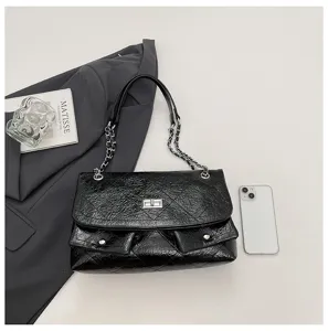 Schwarze gesteppte Schultertasche Detailansicht mit Metallkettenriemen und Drehdruckknopf.