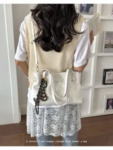 Vista dettagliata di una borsa tote bianca elegante in stile vintage portata a spalla.