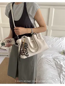 Dettaglio della borsa tote da donna bianca con pelle testurizzata e ciondolo elegante.