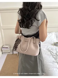 Vista dettagliata di una borsa tote vintage versatile da donna in beige con ciondolo elegante.