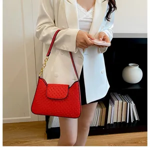 Vue détaillée d'un sac à main rouge en cuir avec chaîne dorée et élégant motif gaufré.