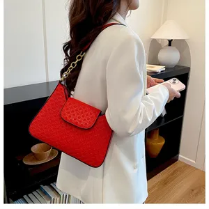 Gros plan sur le sac à épaule rouge élégant avec chaîne dorée et texture gaufrée raffinée.