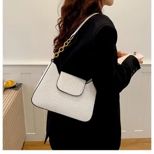 Vue détaillée d'un sac à épaule blanc en cuir embossé avec une bandoulière chaîne dorée.