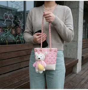 Pink quilted bucket bag detail featuring chain strap and cute bear pendant design.