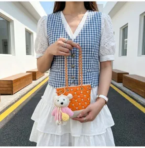 Detail view of Korean style cute rhinestone bucket bag with chain strap and cute bear pendant.
