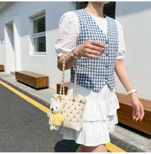 Detailed view of the chic rhinestone quilted bucket bag featuring a cute bear charm and chain strap.