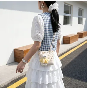 Stylish quilted bucket crossbody bag for women with cute plush bear pendant and diamond accents.