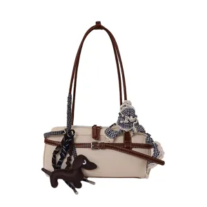 Vintage beige bowling shoulder bag for women with brown straps and cute dog charm accessory.