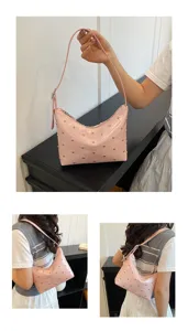 Detailed view of a pink patent leather shoulder bag with metal studs, elegant and chic.