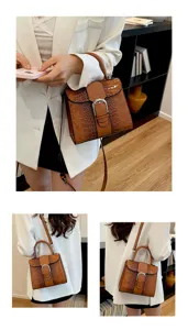 Detail view of the brown crocodile pattern leather handbag with metal buckle and shoulder strap.