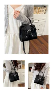 Detailed view of black embossed leather handbag, metal buckle, top handle and shoulder strap.