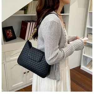Vue détaillée du sac porté épaule noir élégant avec texture tissée chic et chaîne dorée.