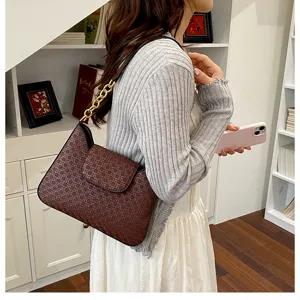 Vue détaillée de l'élégant sac à épaule marron à motif avec chaîne dorée, porté.