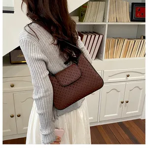 Vue détaillée d'un sac porté épaule marron à monogramme rétro présenté par un mannequin.