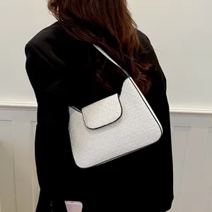 Sac à épaule blanc chic sous les bras avec texture gaufrée élégante et bordure noire stylée.