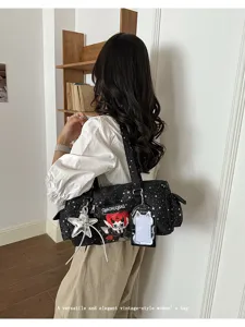 Detailed view of black star print ita bag with cute devil plush and star keychain pendant.