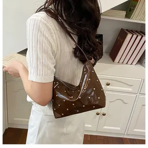 Stylish brown patent leather shoulder bag with chic metal studs, perfect for daily commuting.