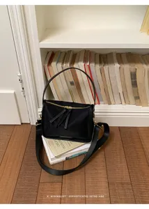 Κομψή μαύρη νάιλον τσάντα χιαστί με χρυσό υλικό και φερμουάρ με φούντες λεπτομέρεια.