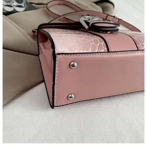 Pink crocodile embossed leather handbag with metal buckle and bottom studs for women.