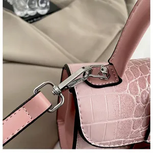Detailed shot of pink crocodile-embossed leather handbag showing hardware and fine texture.