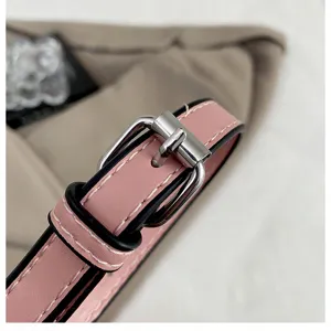 Pink leather bag strap detail with silver metal buckle and contrast stitching, close-up view.