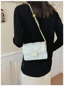 Detail view of the quilted shoulder bag with chain strap and elegant clasp design.