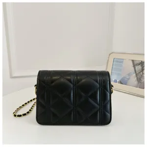Detail shot of black quilted shoulder bag with gold chain strap, stylish and elegant design.
