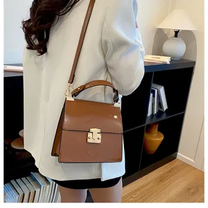 Schicke braune Lackleder Umhängetasche mit Griff und goldenem Verschluss für Damen.