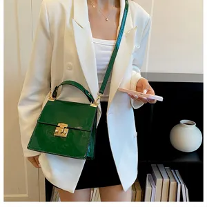 Detailansicht der stilvollen Lackleder Handtasche mit Goldverschluss und Schulterriemen.