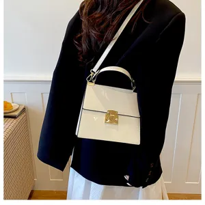Detailansicht der eleganten weißen Handtasche mit edlem Goldverschluss und Ledertextur.