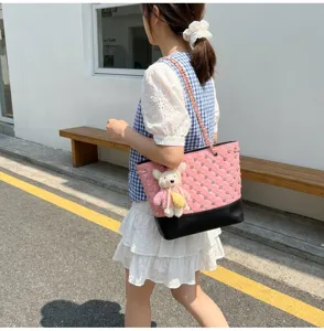 Borsa a tracolla matelassé rosa con catena chic e ciondolo orsetto per look giornaliero.