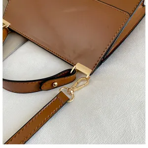 Detailaufnahme einer stilvollen braunen Lackleder Umhängetasche mit goldener Metall Hardware.